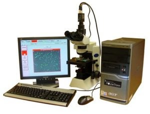 An image depicting the MouseTraxx CASA System. It is a piece of labratory equipment which consists of a small desktop computer screen, keyboard, microscope, computer mouse, and a desktop processor.