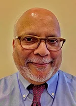 An image of Dr. Ikramuddin Aukhil. He has tanned skin, a beard, is bald, and wears glasses.