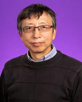 An image of Dr. Donghai Zheng. He wears glasses and has black hair and tanned skin. He is wearing a black shirt; the picture was taken in front of a purple background.